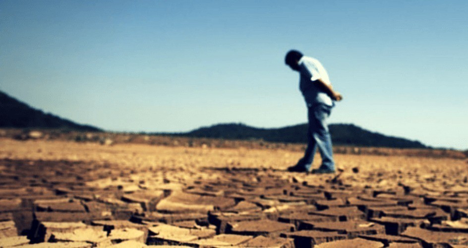 hombre caminando por terreno en sequia